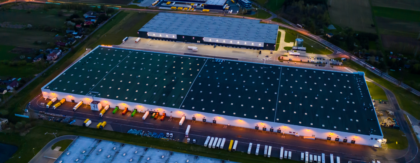 Aerial of commercial warehouse with trucks in parking lot Reply