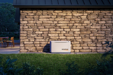 Home standby generator permanently installed next to the stone wall of a home