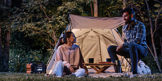 two people camping using a Generac portable power station to light their tent