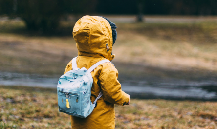 Child wearing raincoat and backpack outside