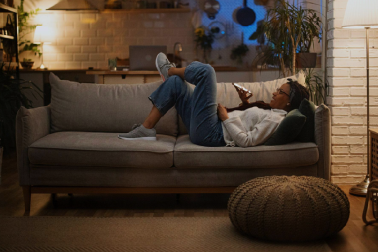 person lounging on their couch in the evening with electricity powering the lights