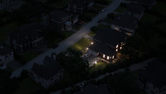 Large aerial view of large home with all the lights on at night.